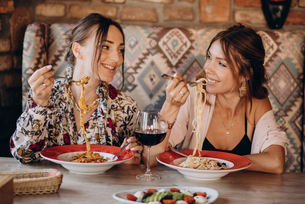 two girls friends eating pasta in an italian restaurant